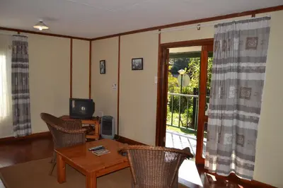 a living room with a table and chairs and a television at Log Cabin & Settlers Village in Graskop