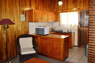 a kitchen with wooden cabinets and a microwave at Log Cabin & Settlers Village in Graskop