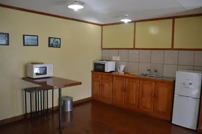 a kitchen with a counter and a microwave and a refrigerator at Log Cabin & Settlers Village in Graskop