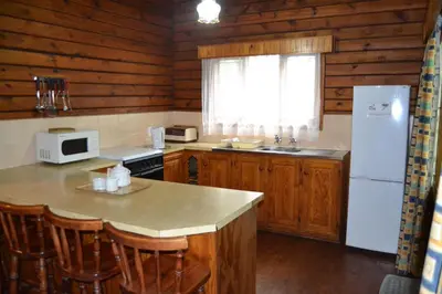 a kitchen with wooden cabinets and a white refrigerator at Log Cabin & Settlers Village in Graskop