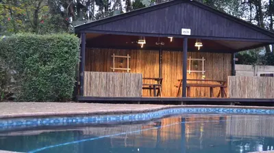 a small building with a swimming pool in front of it at Log Cabin & Settlers Village in Graskop
