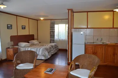 a bedroom with a bed and a table and chairs at Log Cabin & Settlers Village in Graskop
