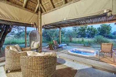 a patio with wicker chairs and a swimming pool at LookOut Safari Lodge in Klipdrift