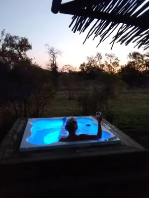 a man in a jacuzzi tub in a field at LookOut Safari Lodge in Klipdrift