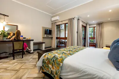 a woman sitting at a desk in a hotel room at Hotel Numbi & Garden Suites in Hazyview