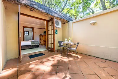 a patio with a table and chairs and a bedroom at Hotel Numbi & Garden Suites in Hazyview