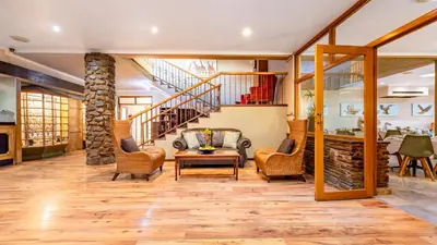 a living room with wooden floors and a staircase at Hotel Numbi & Garden Suites in Hazyview