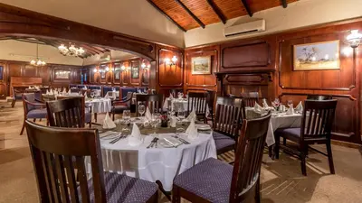 a restaurant with tables and chairs in a room at Hotel Numbi & Garden Suites in Hazyview