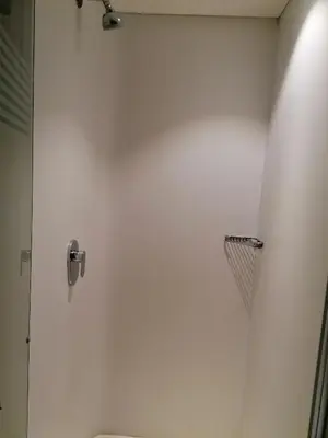 a bathroom with a shower and a white wall at SUN1 WITBANK in Witbank