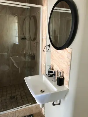 a bathroom with a sink and a shower and a mirror at Favour Guest house in Polokwane