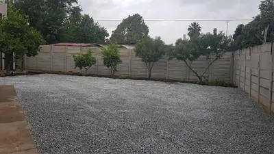 a driveway in front of a fence with trees at Favour Guest house in Polokwane
