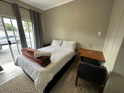a bedroom with a bed and a table with a chair at Favour Guest house in Polokwane