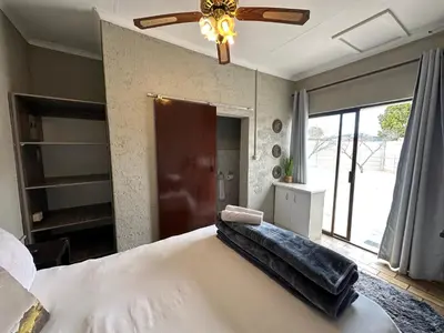a bedroom with a large bed with a ceiling fan at Favour Guest house in Polokwane