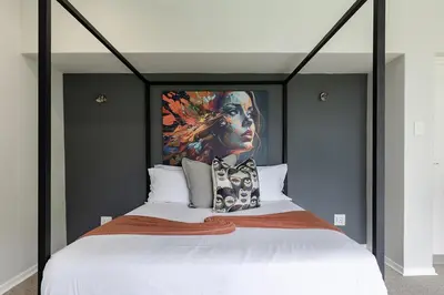 a bedroom with a large bed with a painting on the wall at Matumi Golf Lodge in Nelspruit