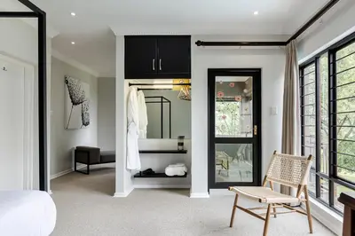 a bedroom with a bed and a chair and a mirror at Matumi Golf Lodge in Nelspruit