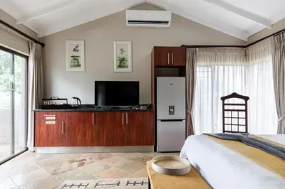 a bedroom with a refrigerator and a tv at Matumi Golf Lodge in Nelspruit
