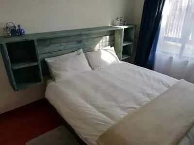 a bedroom with a white bed with a wooden headboard at Home @ Harry's in Pretoria