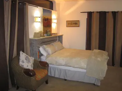 a bedroom with a bed and a chair in a room at Home @ Harry's in Pretoria