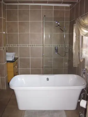 a bath tub in a bathroom with a shower at Home @ Harry's in Pretoria