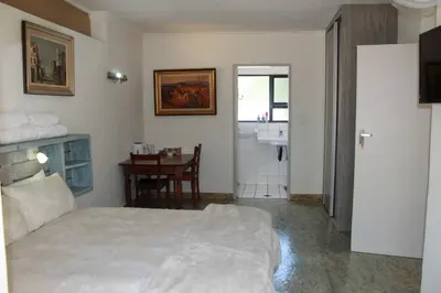 a bedroom with a bed and a table and a bathroom at Home @ Harry's in Pretoria