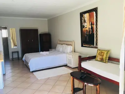 a bedroom with two beds and a table and a chair at At The Rocks Country Estate in Avondzon