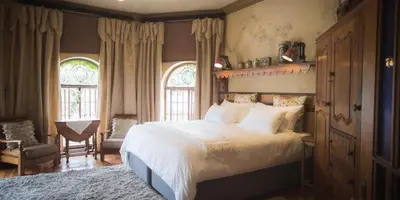 a bedroom with a bed and a chair and windows at Schoon Huis Manor in Kempton Park