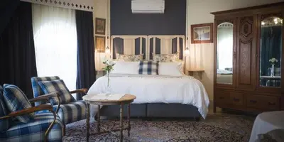 a bedroom with a bed and a table and a chair at Schoon Huis Manor in Kempton Park