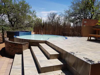 a swimming pool with a bench in a patio at Cottage Lenise in Phalaborwa