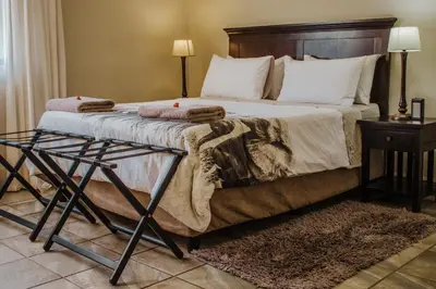 a bedroom with a large bed with a wooden headboard at Cottage Lenise in Phalaborwa