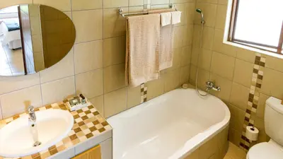 a bathroom with a tub and a sink and a mirror at Cuckoo Ridge Country Retreat in Hazyview