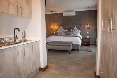 a bedroom with a bed and a kitchen with a sink at Iso'Bella Vita Guesthouse in Phalaborwa