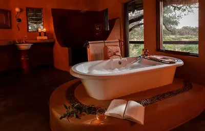 a bath tub in a bathroom with a window at Pondoro Game Lodge in Balule Game Reserve