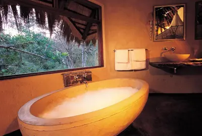a large wooden tub in a bathroom with a window at Pondoro Game Lodge in Balule Game Reserve