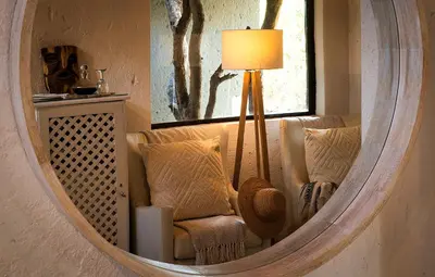 a mirror in a room with a chair and a lamp at Pondoro Game Lodge in Balule Game Reserve