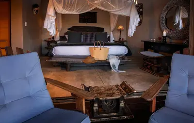a bedroom with a bed with a table and two chairs at Pondoro Game Lodge in Balule Game Reserve