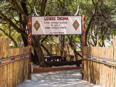 a sign in front of a park with trees at aha Lesedi African Lodge & Cultural Village in Pelindaba