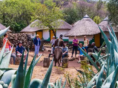 a man riding an elephant in front of a group of people at aha Lesedi African Lodge & Cultural Village in Pelindaba