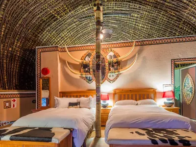 a bedroom with two beds and a chandelier at aha Lesedi African Lodge & Cultural Village in Pelindaba