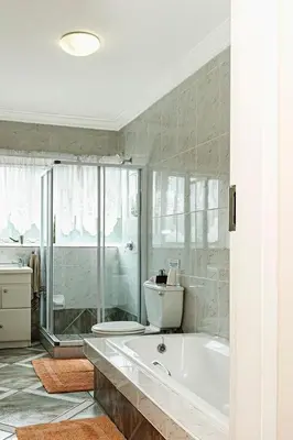 a white bathroom with a tub and a shower at Glenda's Guest Suites in Midrand