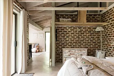 a bedroom with a brick wall and a bed at Glenda's Guest Suites in Midrand