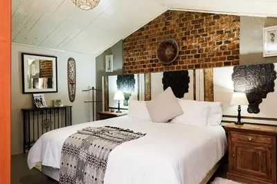 a bedroom with a large white bed with a brick wall at Glenda's Guest Suites in Midrand