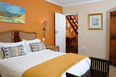 a bedroom with a large white bed with orange walls at Stonecutters Lodge in Dullstroom