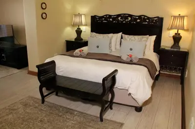 a bedroom with a large bed with a chair and two lamps at Del Roza Guest House in Middelburg