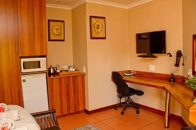 a kitchen with a desk with a computer and a microwave at Del Roza Guest House in Middelburg
