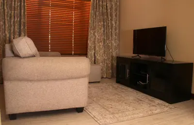 a living room with a chair and a flat screen tv at Del Roza Guest House in Middelburg