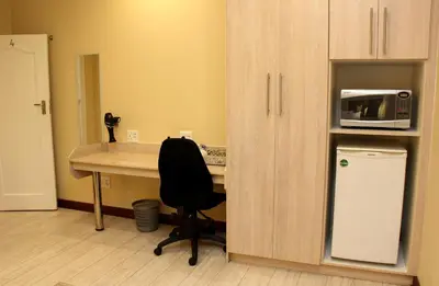 a office with a desk with a chair and a microwave at Del Roza Guest House in Middelburg