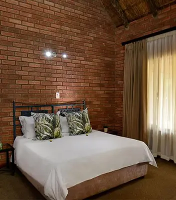 a bedroom with a large bed in a brick wall at Monateng Safari Lodge in Wallmannstal