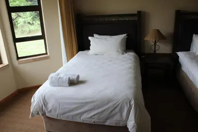 a bedroom with a white bed with two towels on it at Monateng Safari Lodge in Wallmannstal