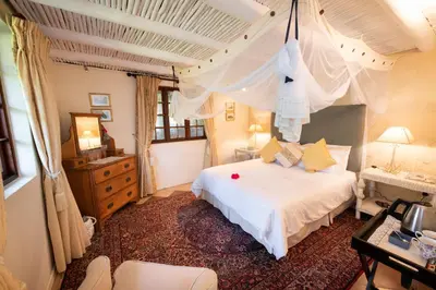 a bedroom with a large white bed and a desk at Blyde River Canyon Lodge in Hoedspruit