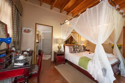 a bedroom with a canopy bed with a desk and a bed istg at Blyde River Canyon Lodge in Hoedspruit